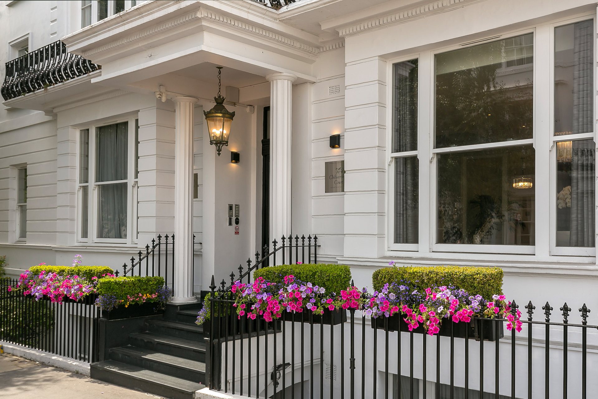 The entrance to Chilworth Court on Chilworth Street — white portico, black railings and flower boxes